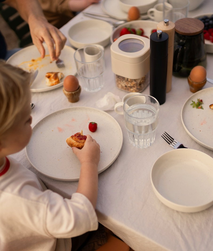 Kind aan de buitentafel bij het ontbijt, met croissants en aardbeien
