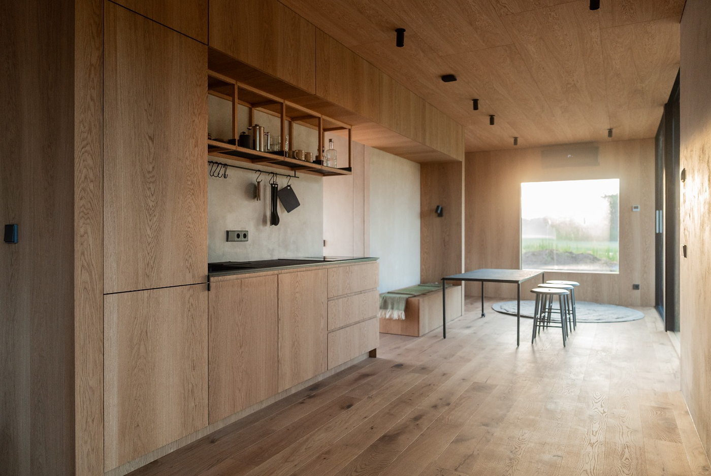 Doorkijk door de lodge: de eiken keukenwand met daarachter de eettafel bij het raam