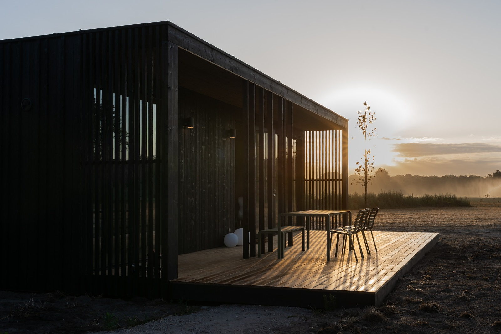 Eco by Nature lodge in het eerste ochtendlicht, met de zon laag achter de bomen